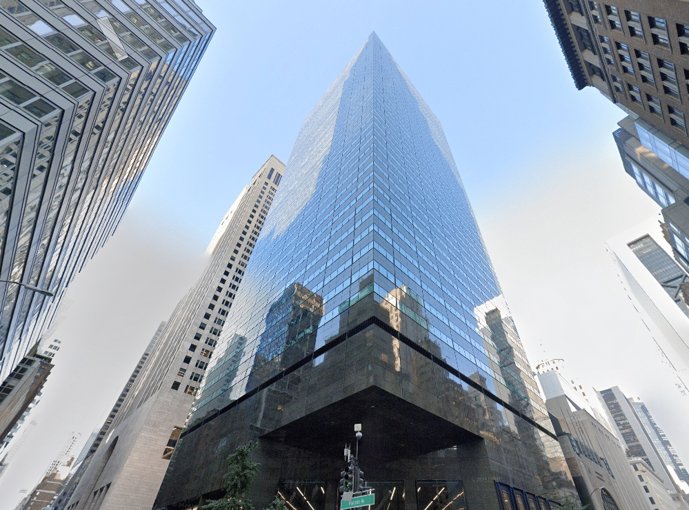 Modern skyscraper with glass facade against a blue sky at 590 Madison.