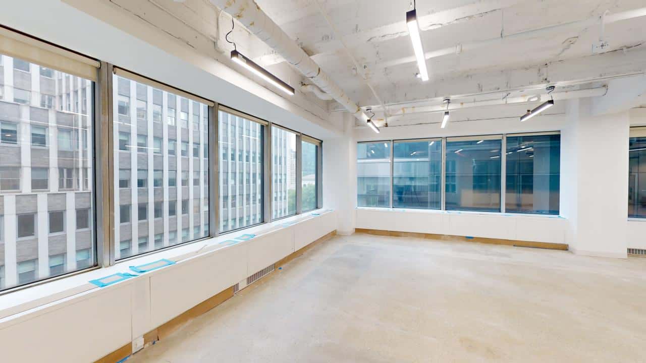 Demolished office with large windows and concrete floors.