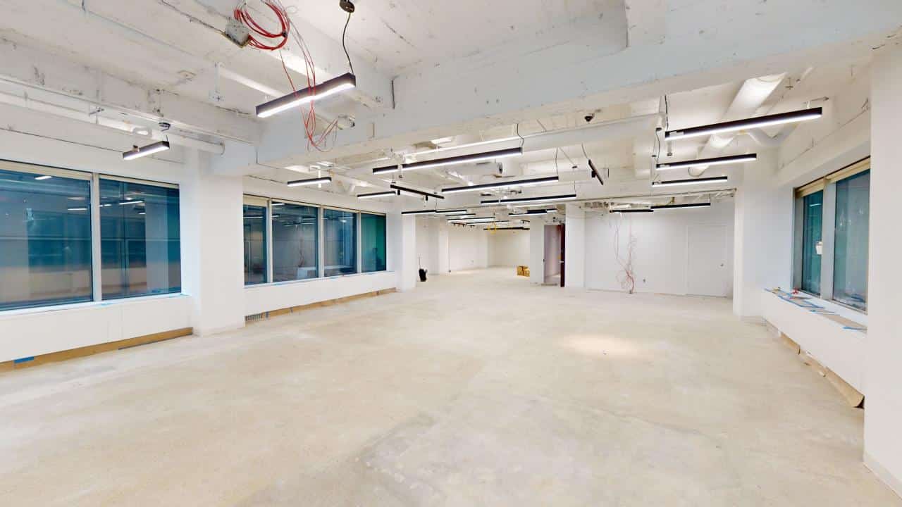 Spacious empty office with large windows and exposed ductwork.