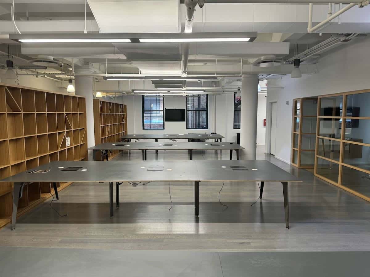 Office with wooden shelves, work tables, and large windows.