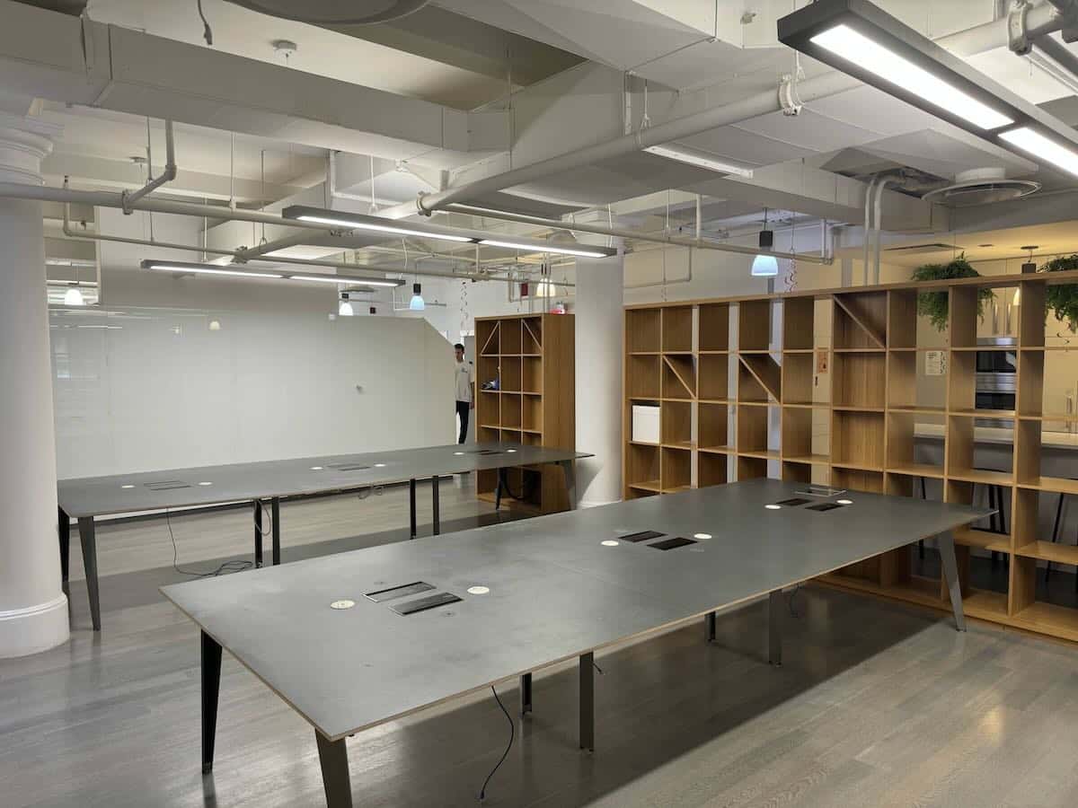 Open office with gray tables, wooden shelves, and hardwood floors.