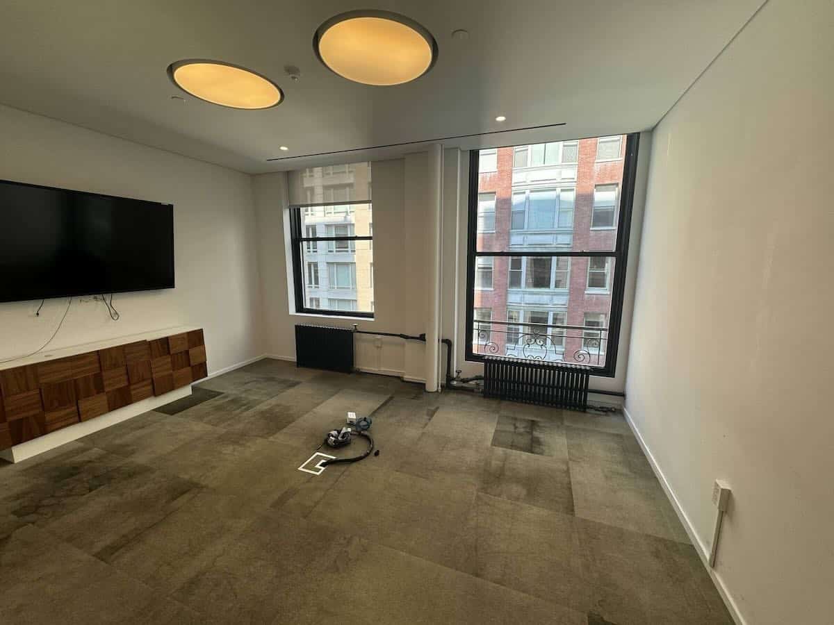 Minimalist room with beige carpet, wall TV, windows, recessed lights.