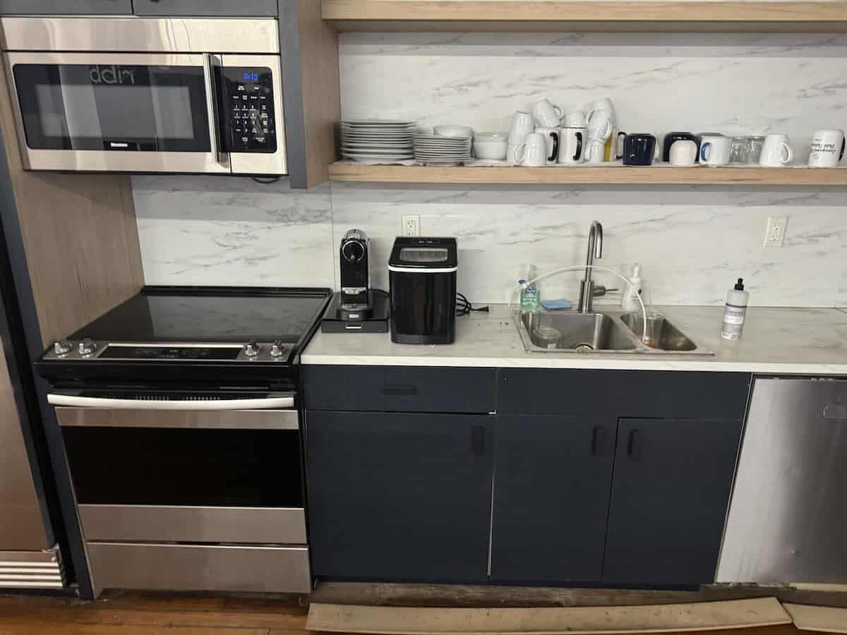 A kitchen counter with various appliances and shelves above.