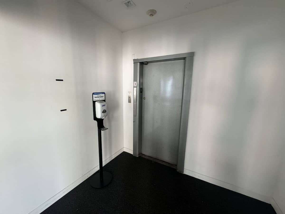 A small area with an elevator door and a hand sanitizer dispenser.