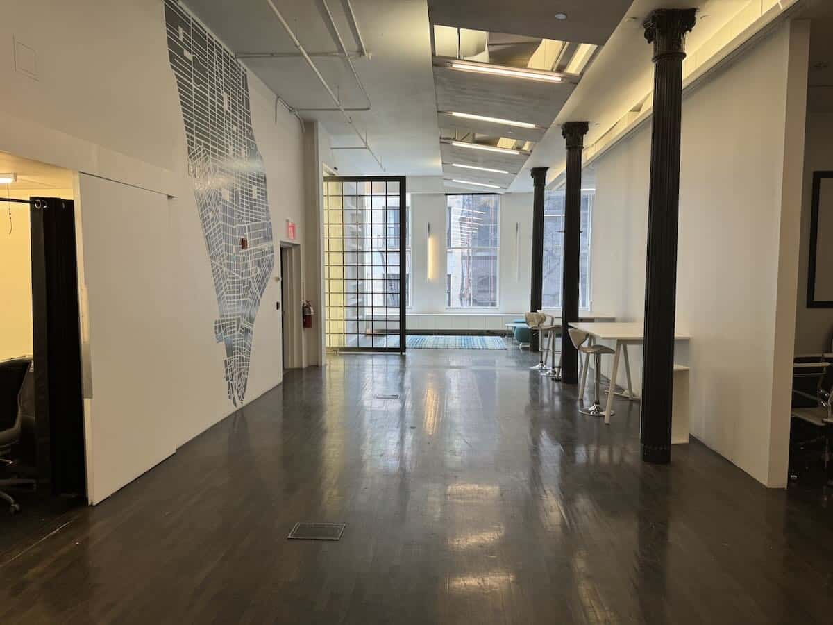 Modern office hallway with seating, dark floors, and a map on the wall.