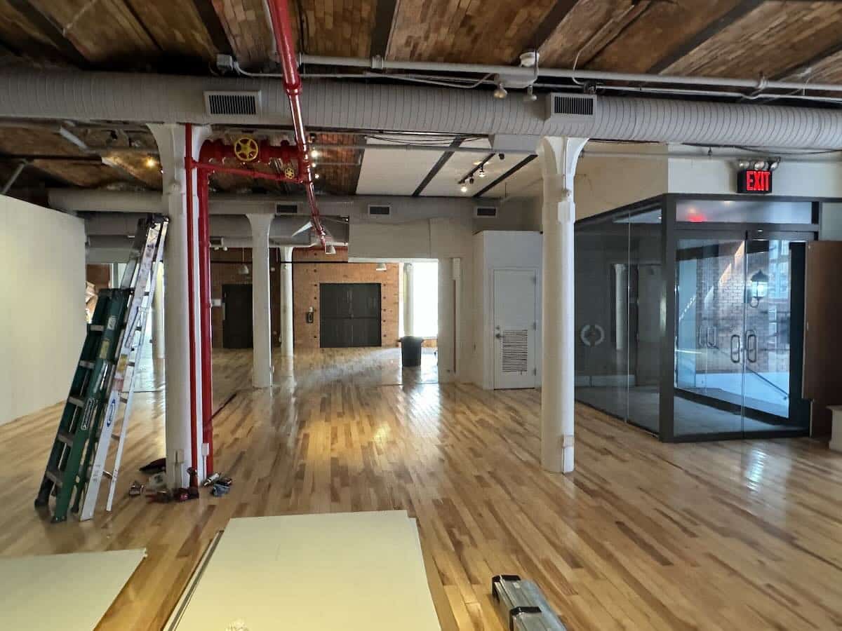 A spacious, unfinished room with exposed brick walls, wooden floors.