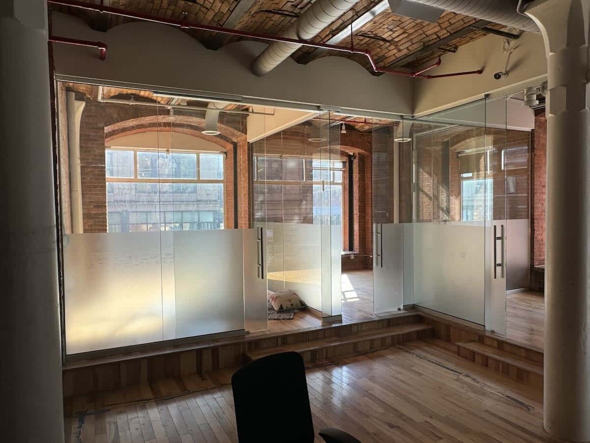 Office with wooden floors, brick walls, and glass-walled meeting room.