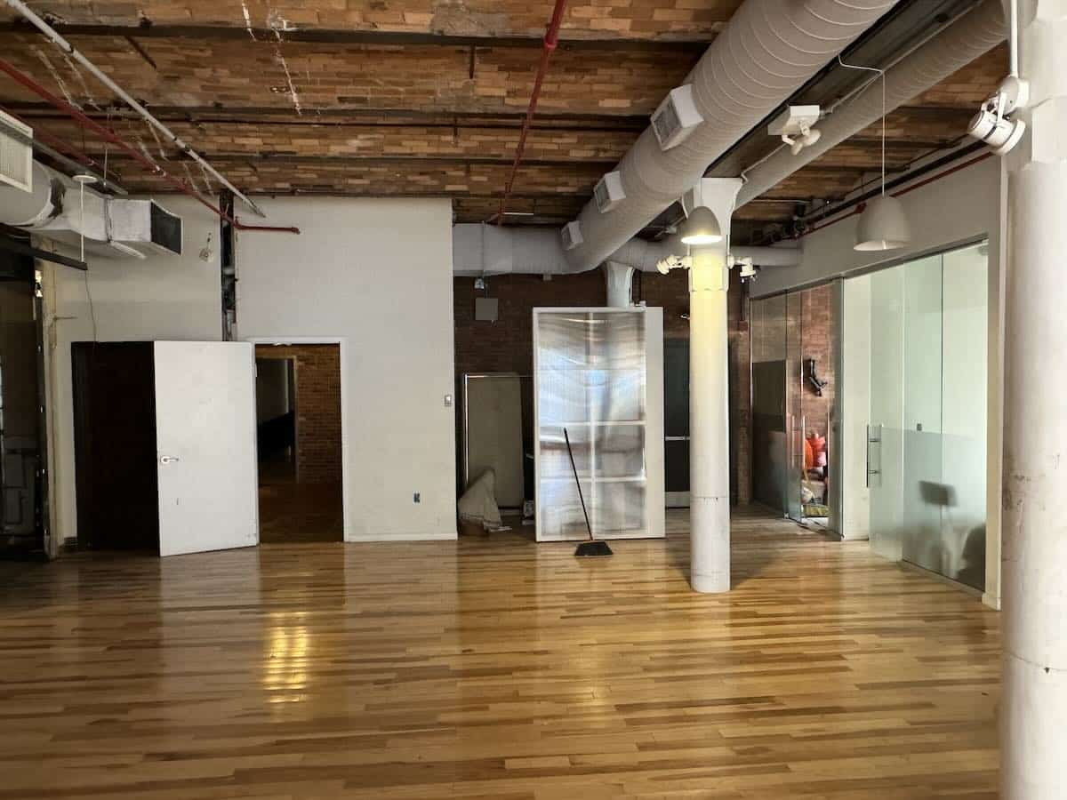 An empty room with a wooden floor and exposed brick walls.