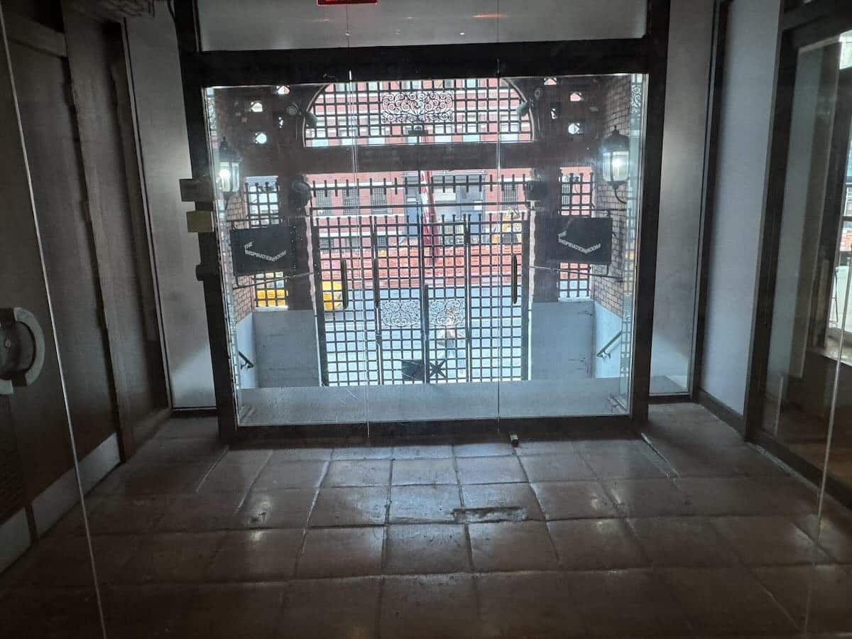 Bright indoor space with glass door, revealing outdoor gated area and brick building.