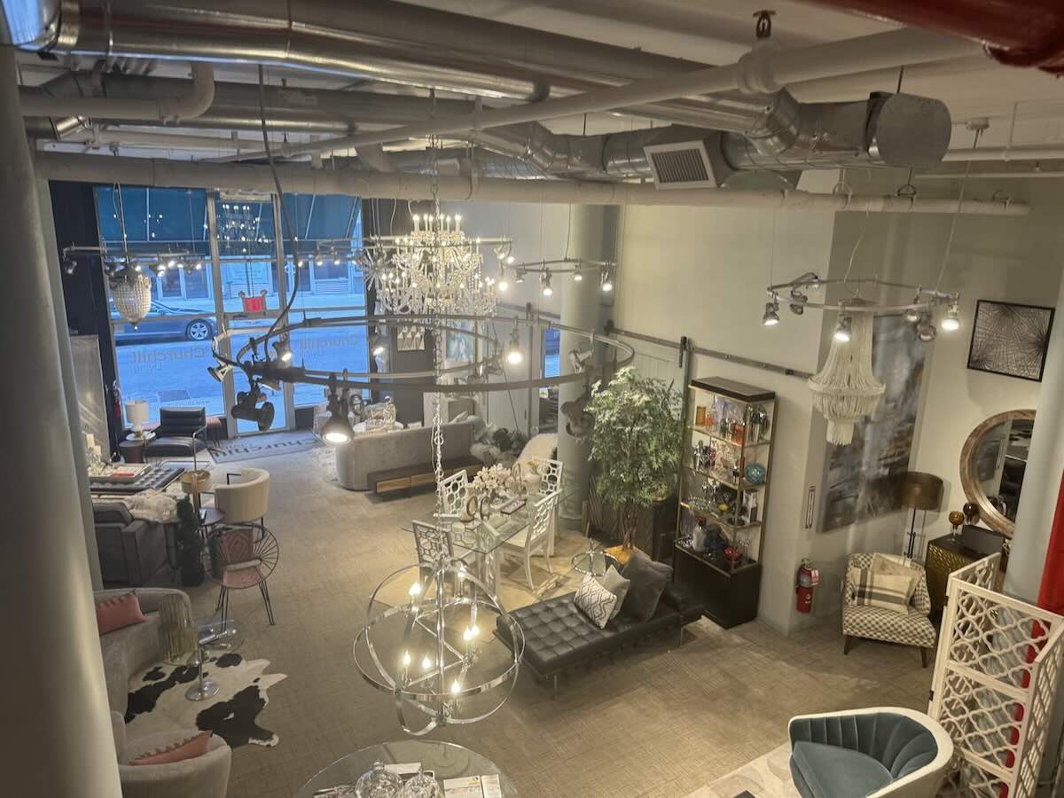 ALT tag: "Industrial-style showroom with furniture and hanging lights.