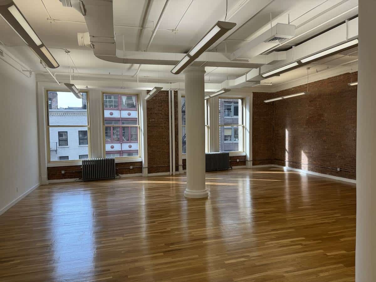 Polished wooden floors, brick walls, large windows in a spacious room.