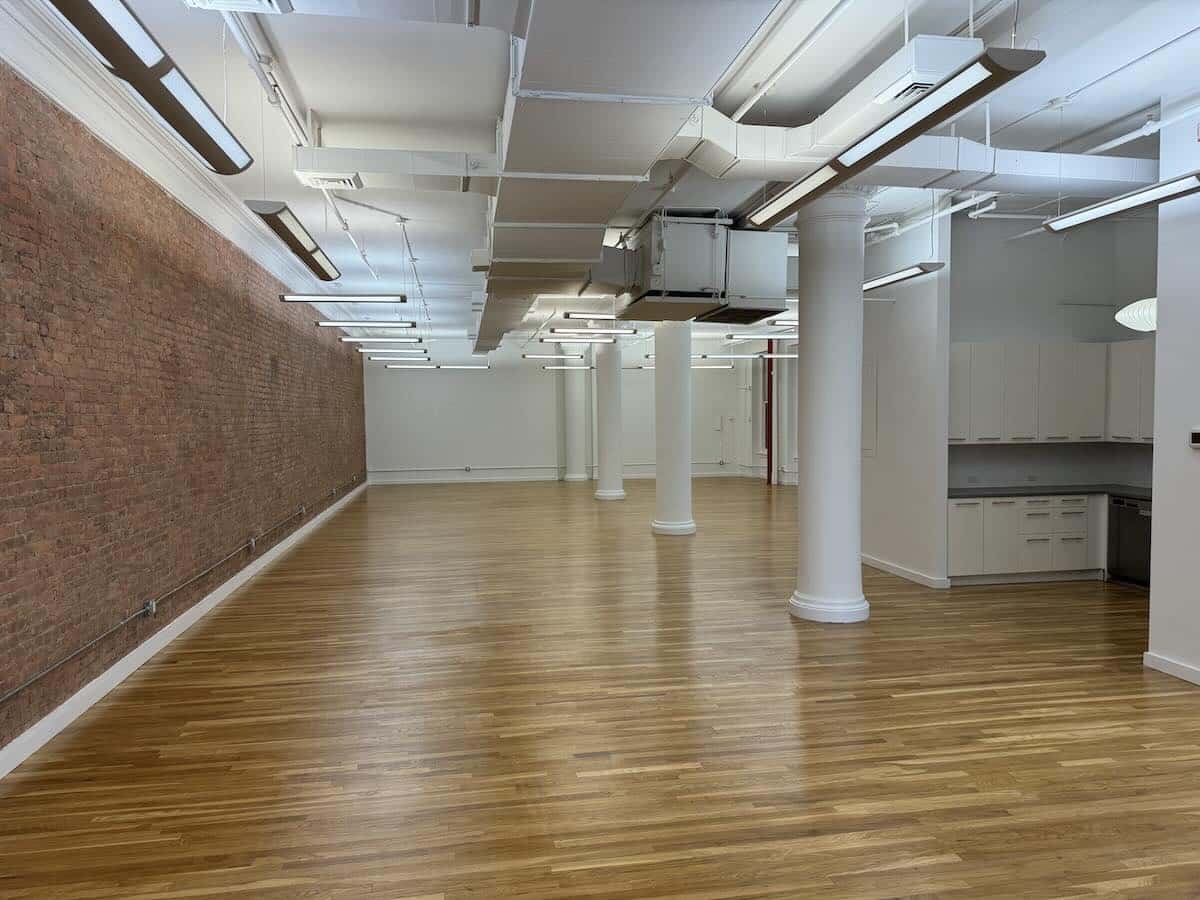 Spacious room with wood floors, brick walls, and white columns.