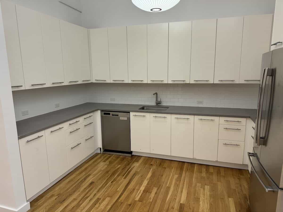 A modern kitchen with white cabinets, stainless steel appliances, and gray countertops.