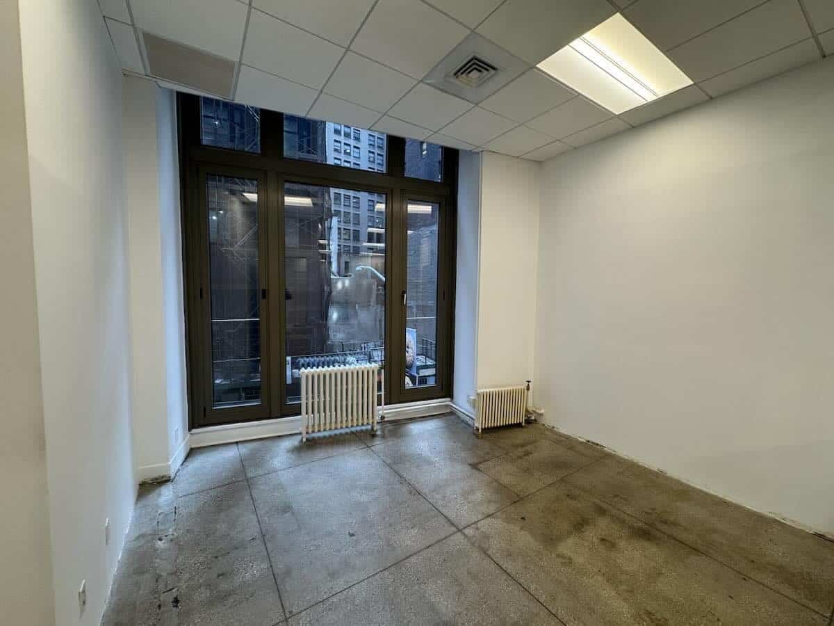 Empty office with large windows and concrete floor at 15 Maiden Lane.