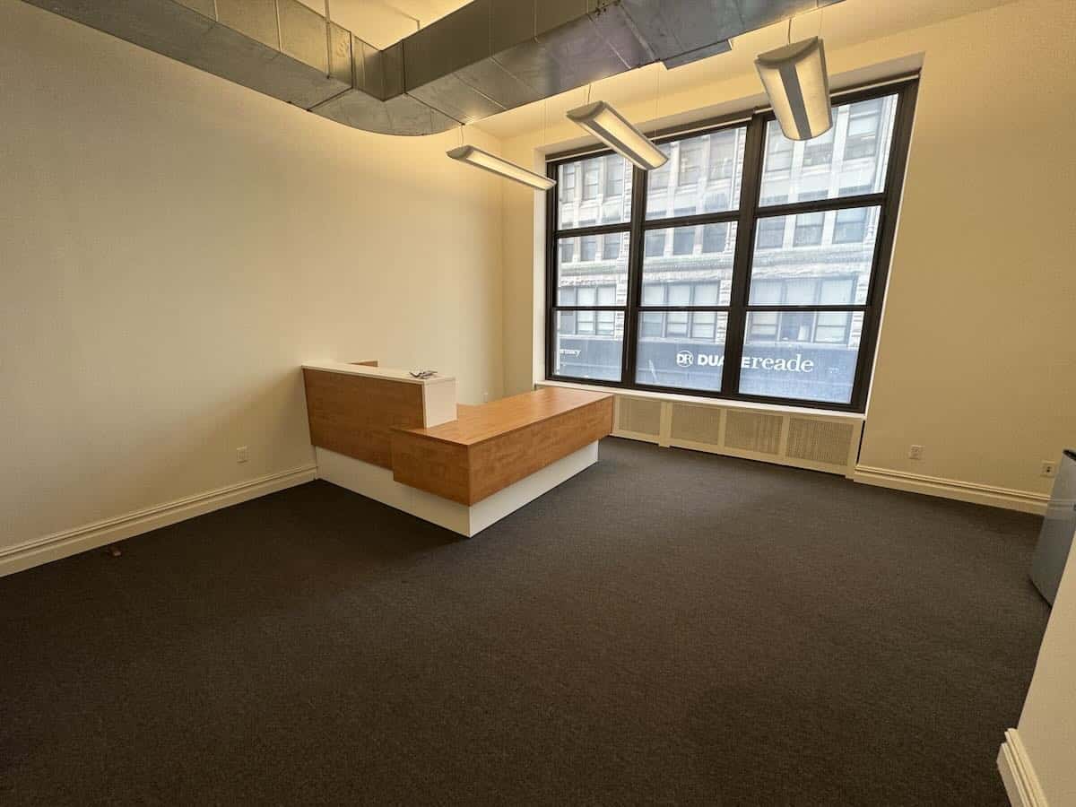 Minimalist office at 299 Broadway, suite 200, with street view window.