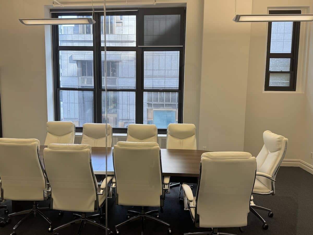 Modern conference room with long wooden table and eight white chairs.