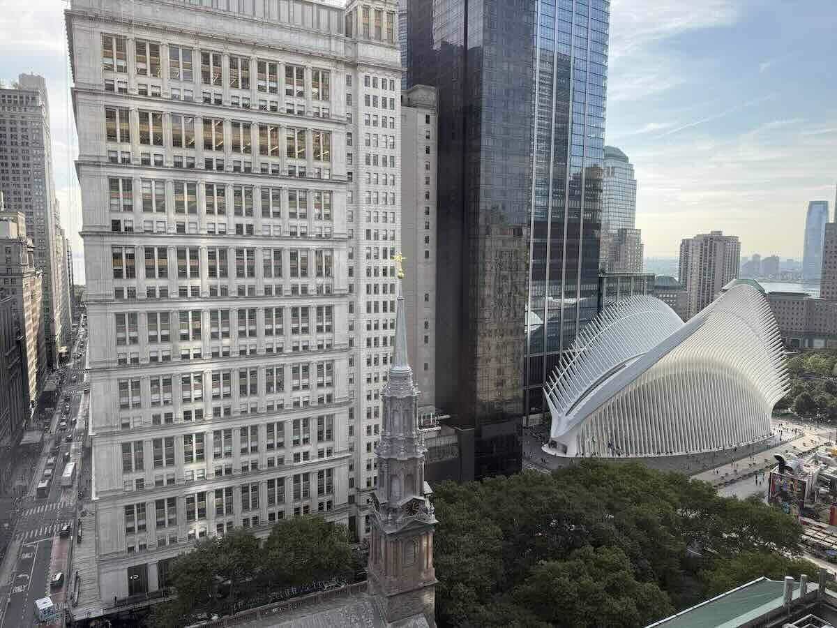 Cityscape with modern white structure and older ornate building under clear sky.