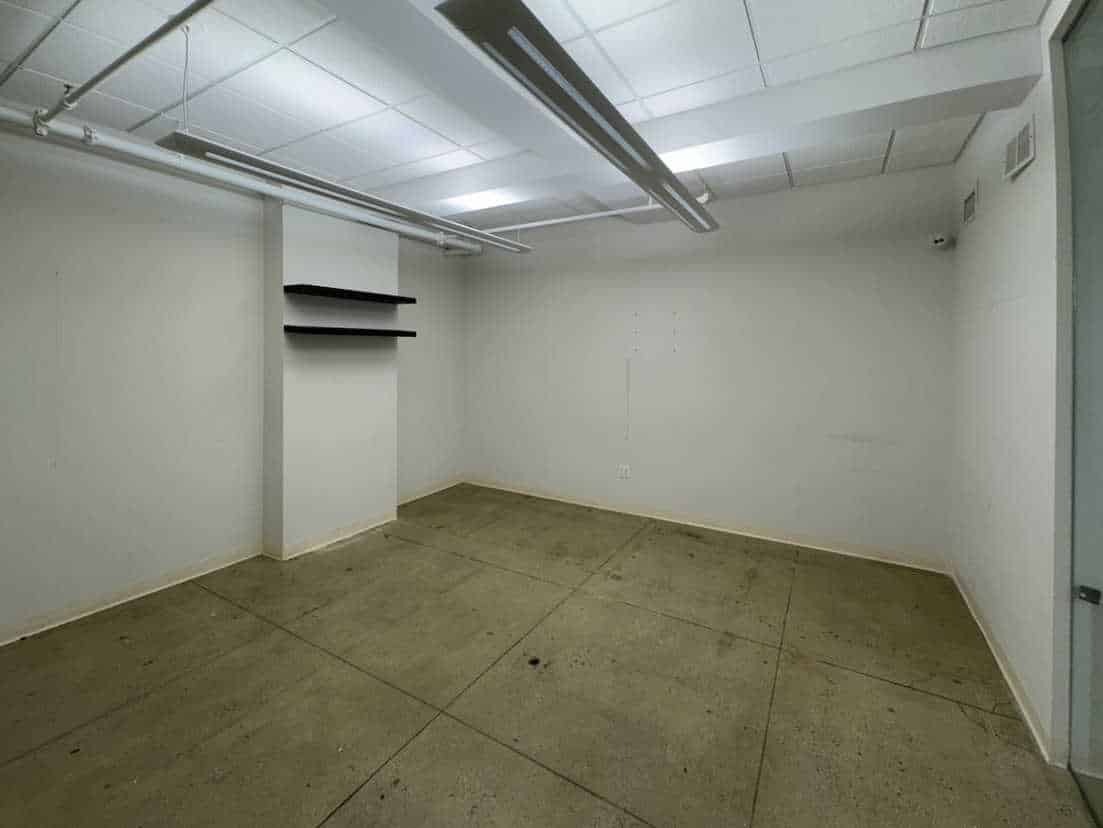 Minimalist room with concrete floors, white walls, and a white grid ceiling.