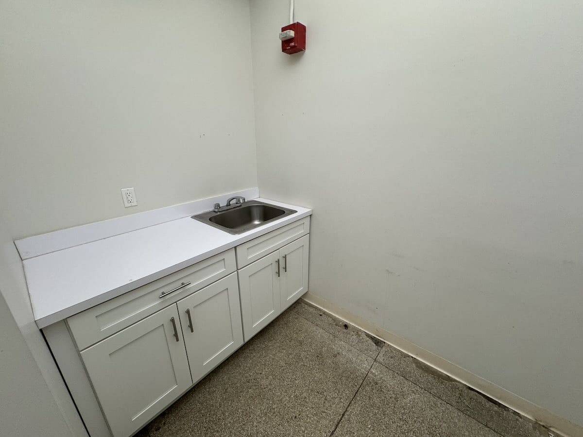 Room with white sink, silver handles, grey walls, and emergency light.