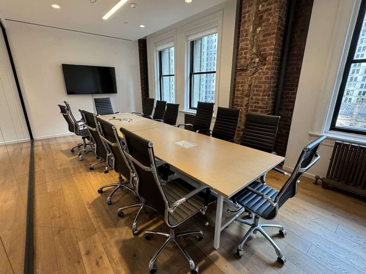 A modern conference room with a long table and black chairs.