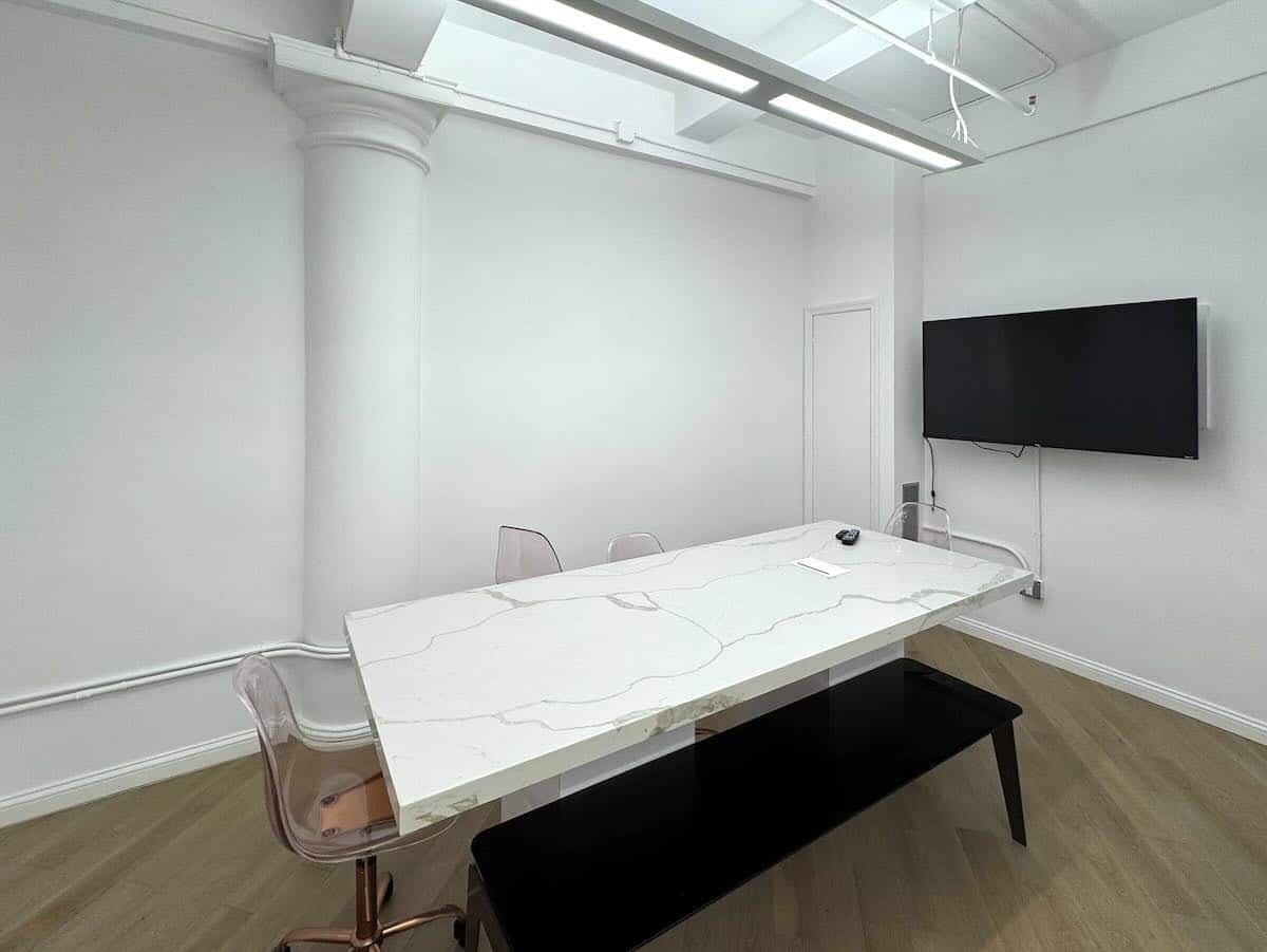 Minimalist meeting room with TV, marble table and clear chairs