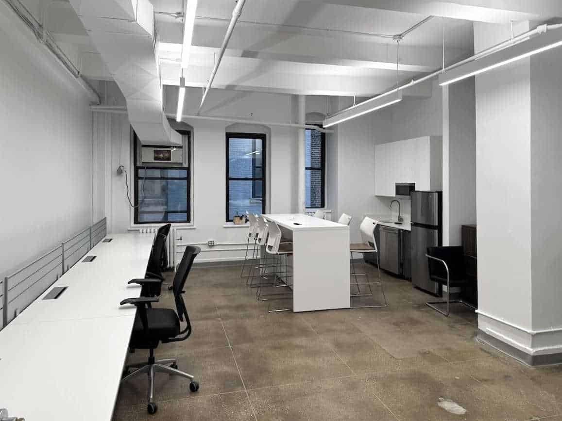 Modern office with white walls, high ceilings, and long office desk.