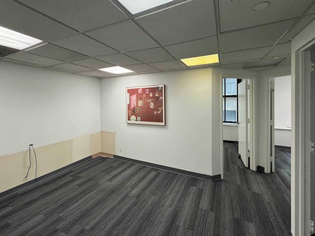 Empty room with gray carpet, white walls, and framed picture.