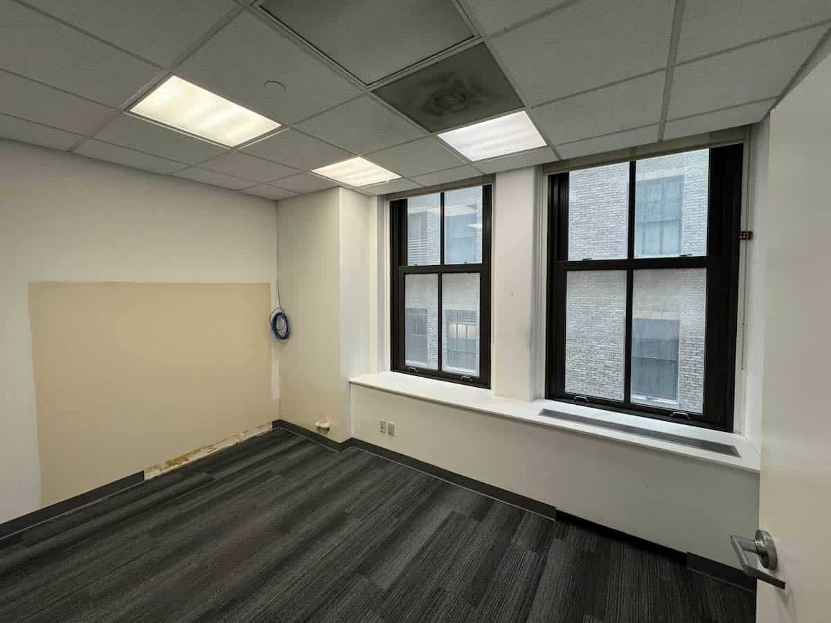 Small, empty office with large windows and carpeted floor