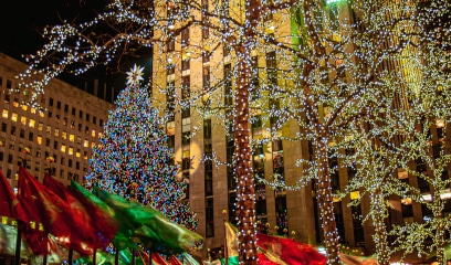 Rockefeller Center Christmas tree beautifully illuminated against a backdrop of NYC skyscrapers