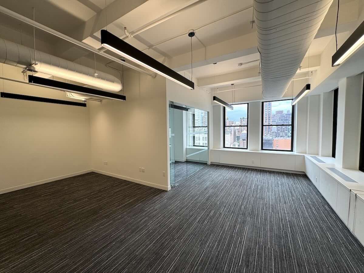 Modern office at 215 Park Ave South with large windows and city view.