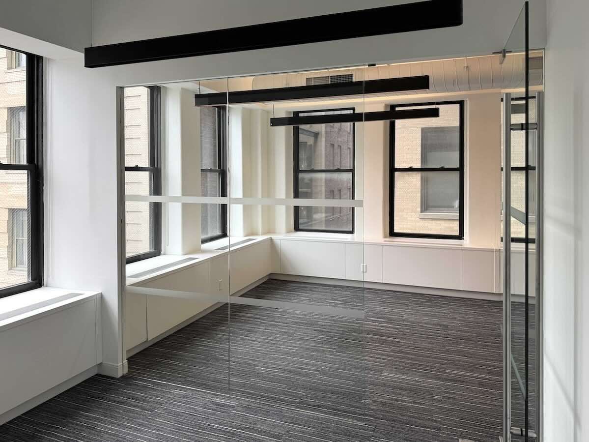 Modern office with large windows and gray carpet.