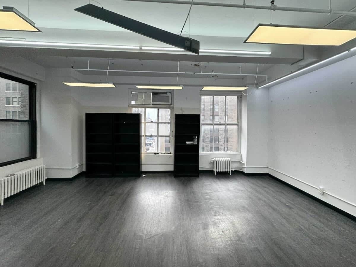 Office space with wood floors, large windows, and black shelving.