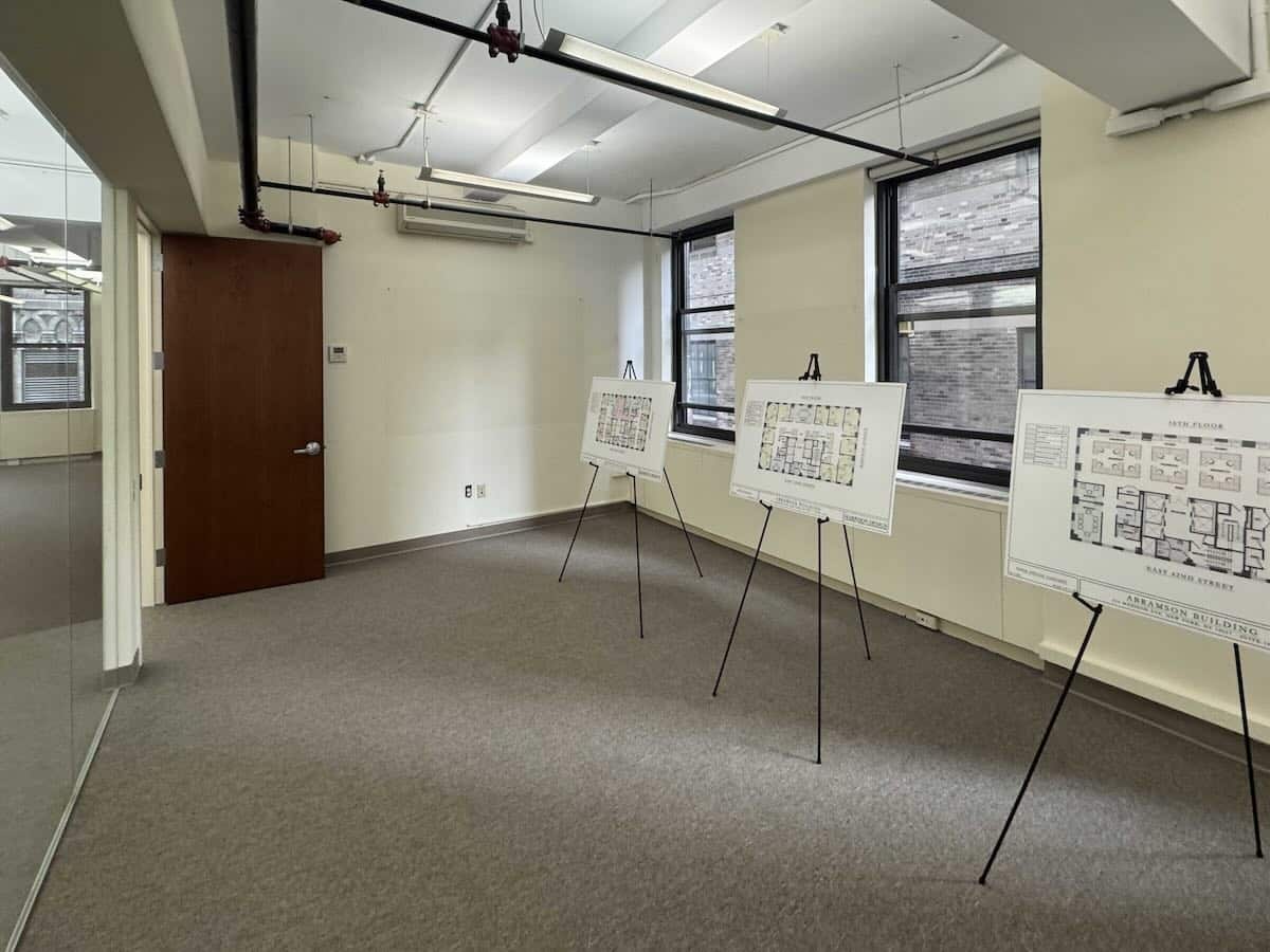 Room with easels and floor plans, natural light filtering through windows.