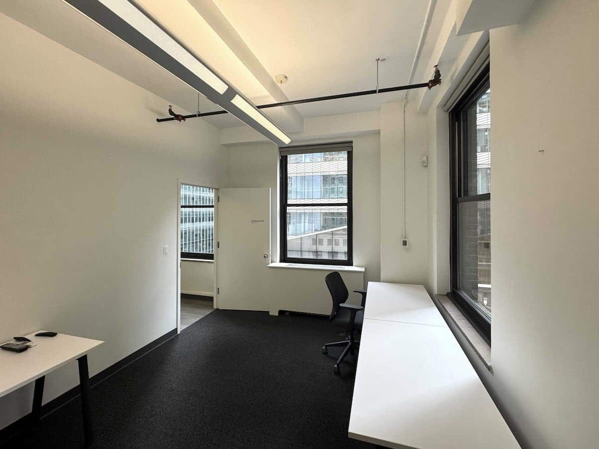 Modern office on Madison Ave: white walls, large windows, black carpet.