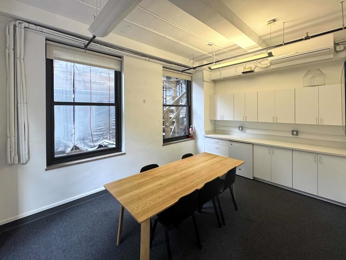 Modern office with long table, black chairs, and large windows.