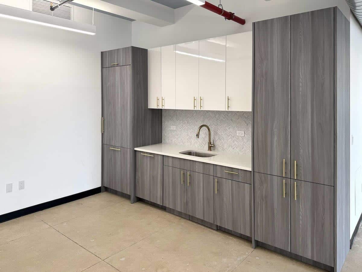 Modern kitchen with gray cabinets, white stone countertop, and faucet