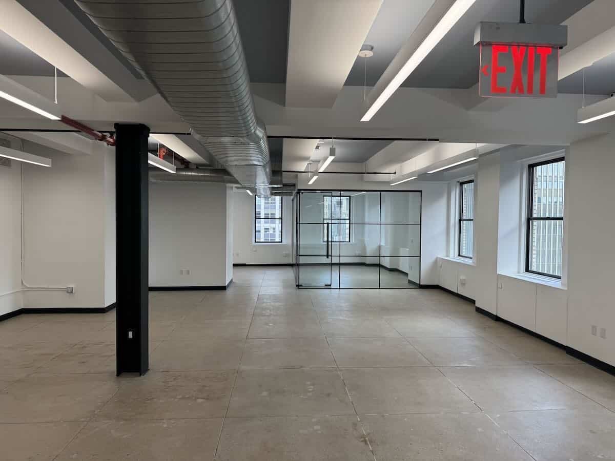 Modern office with large windows, concrete floors, and white walls.