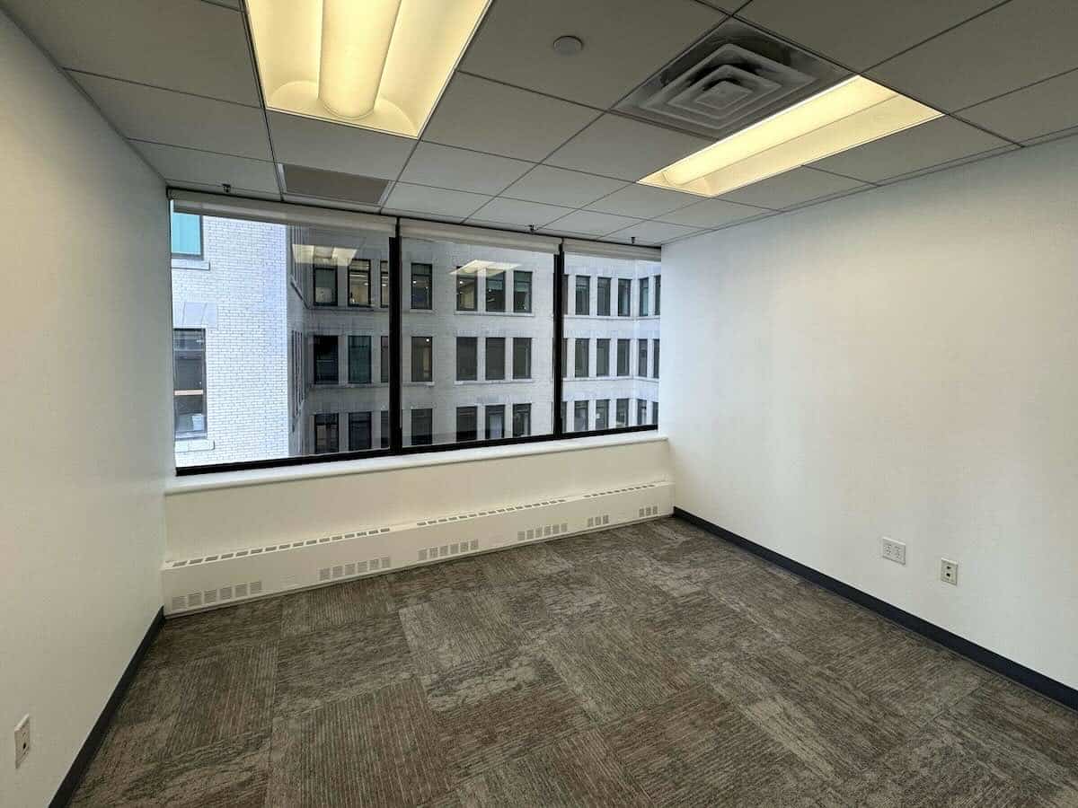 Office with gray carpet, white walls, and large window view.