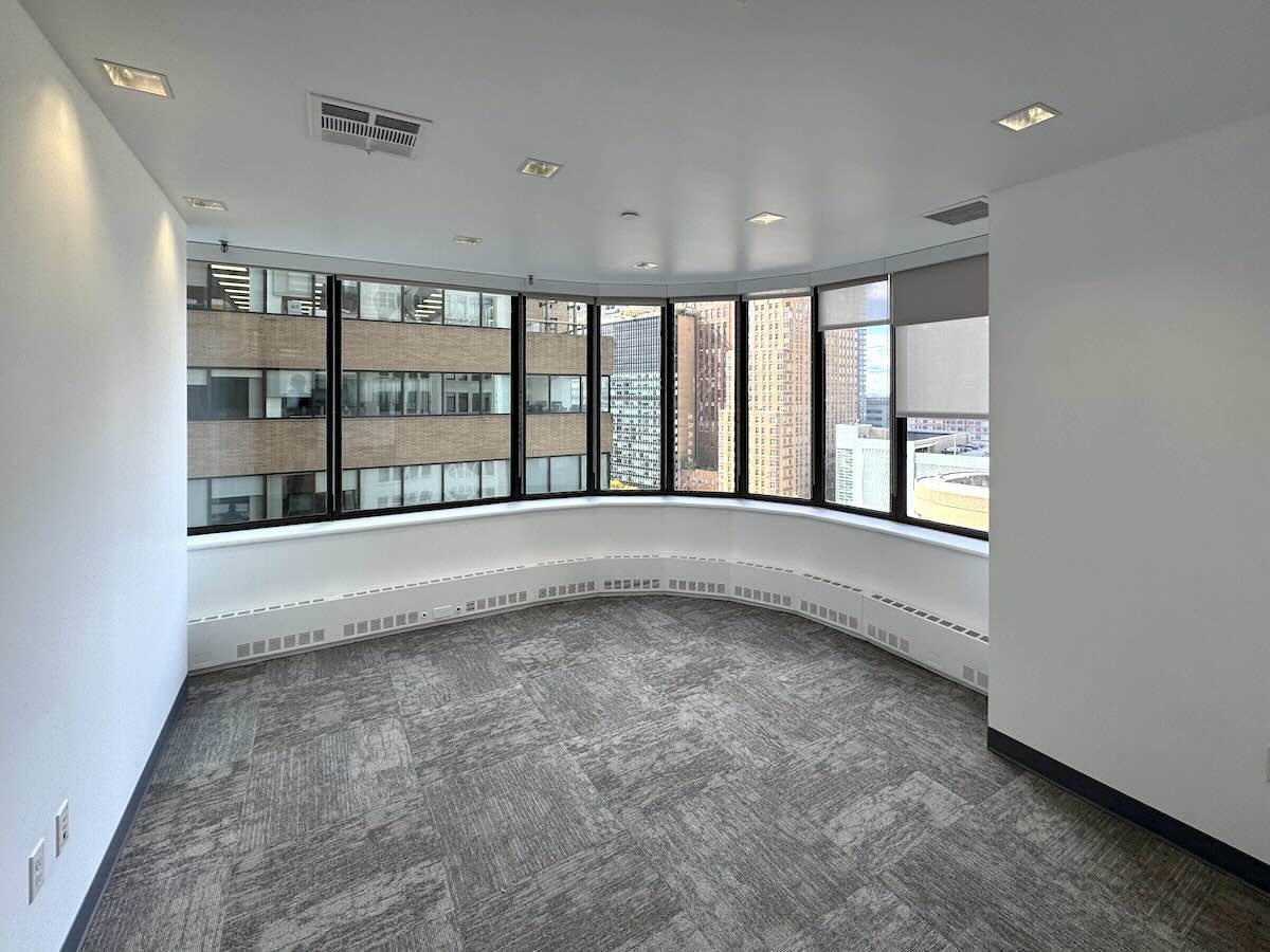 Modern office with carpet, white walls, and view of skyscrapers