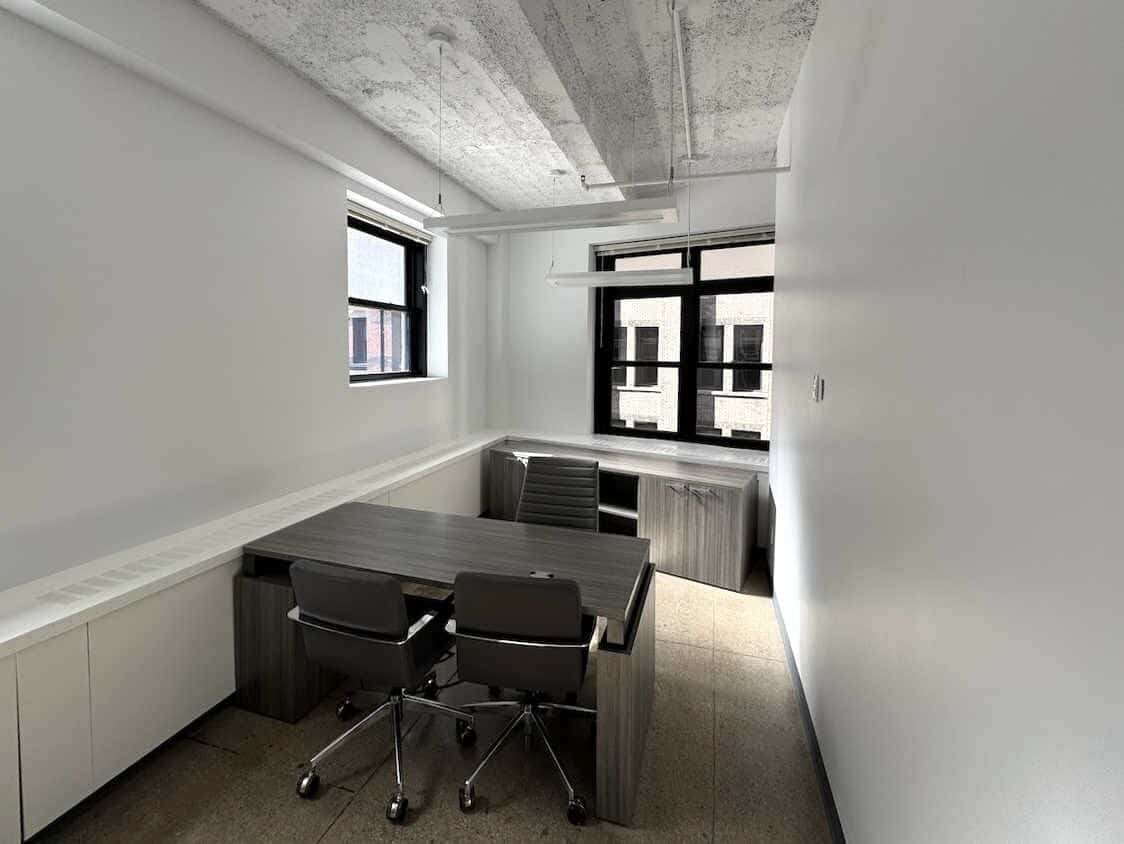 L-shaped desks with gray chairs in sunny, minimalist office.