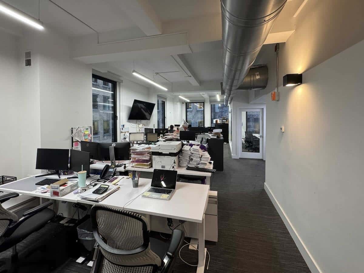 Modern office with desks, computers, and large TV.