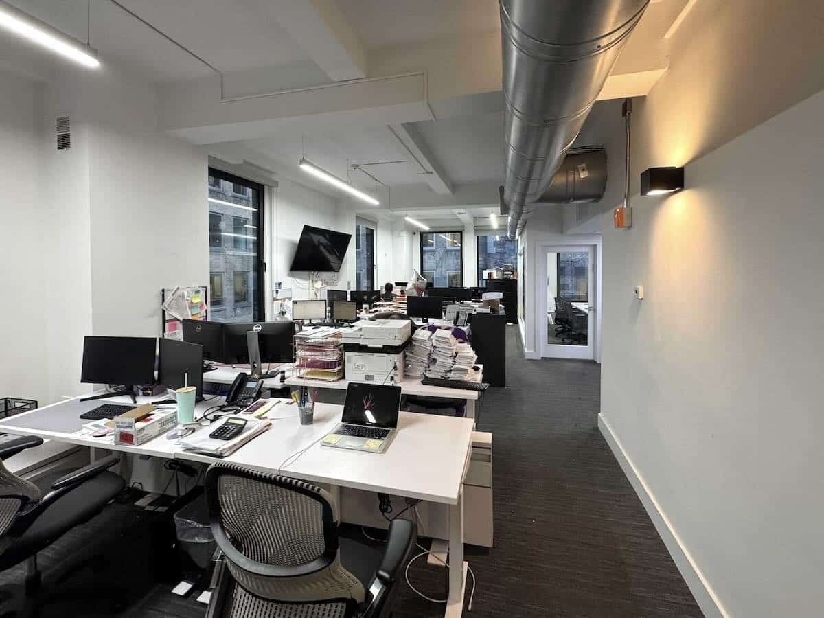 Modern 7th-floor office with desks, computers, and large windows.