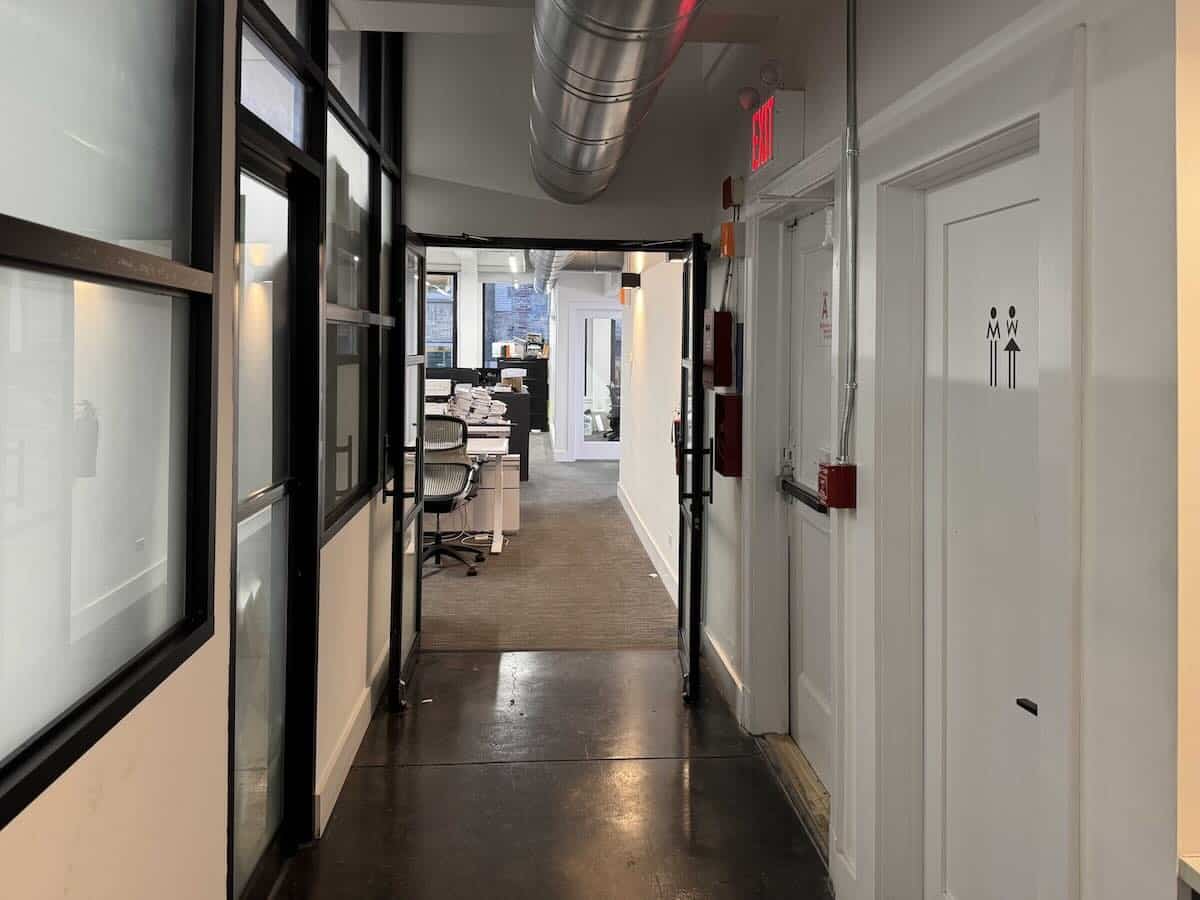 hallway with glass walls, office space, and exit sign.