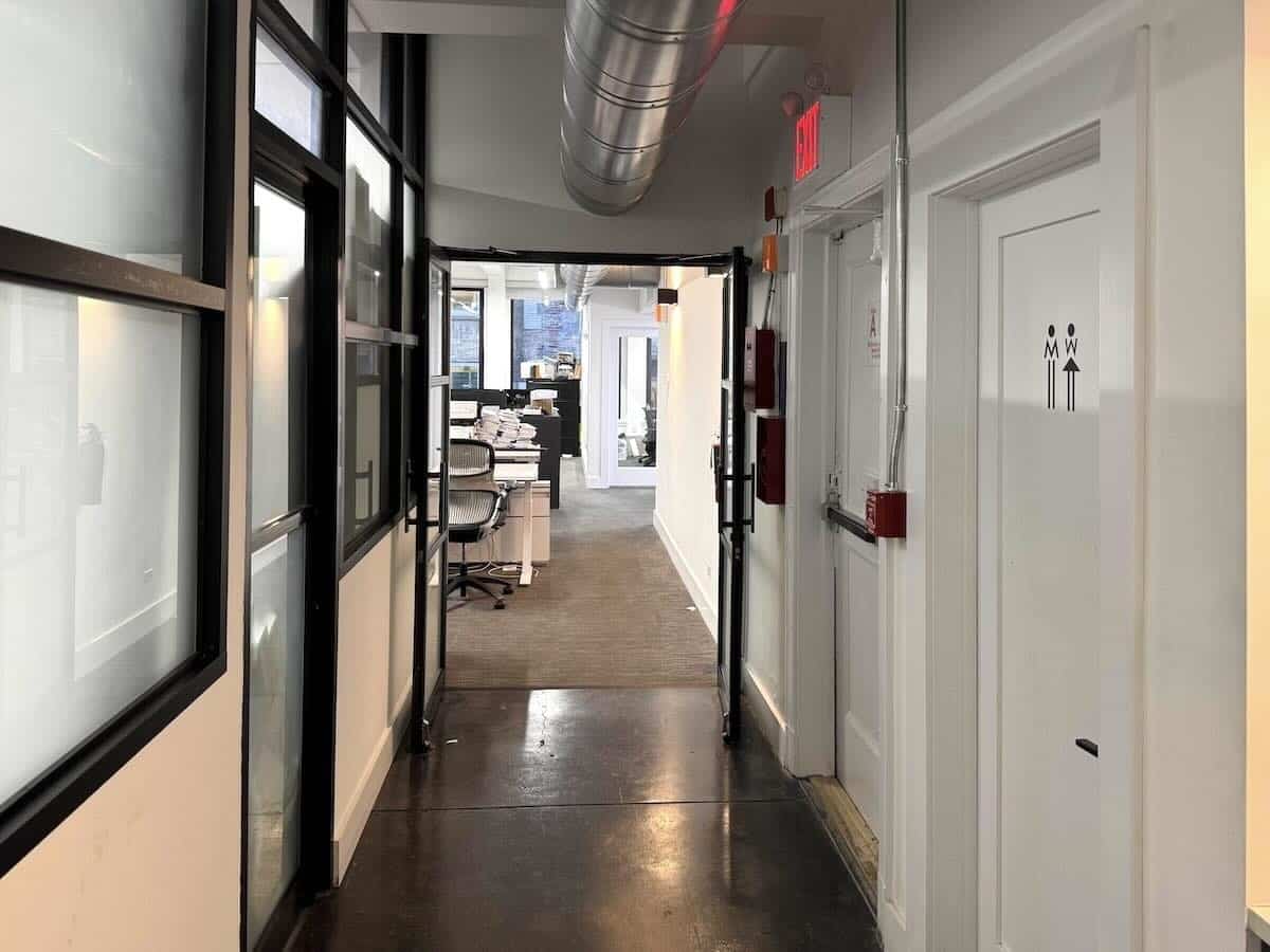 7th Floor corridor leading to office space with desks and restroom.