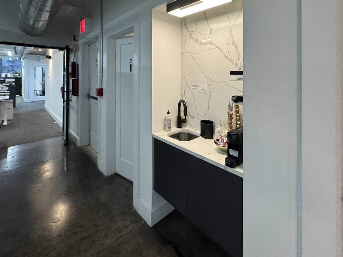 Kitchenette on with sink, coffee maker, and cabinets.