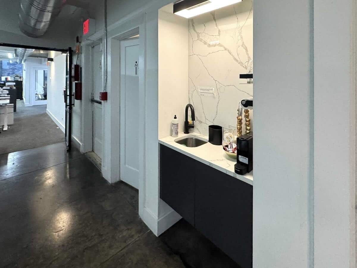 kitchenette with sink, black cabinets, and coffee maker.