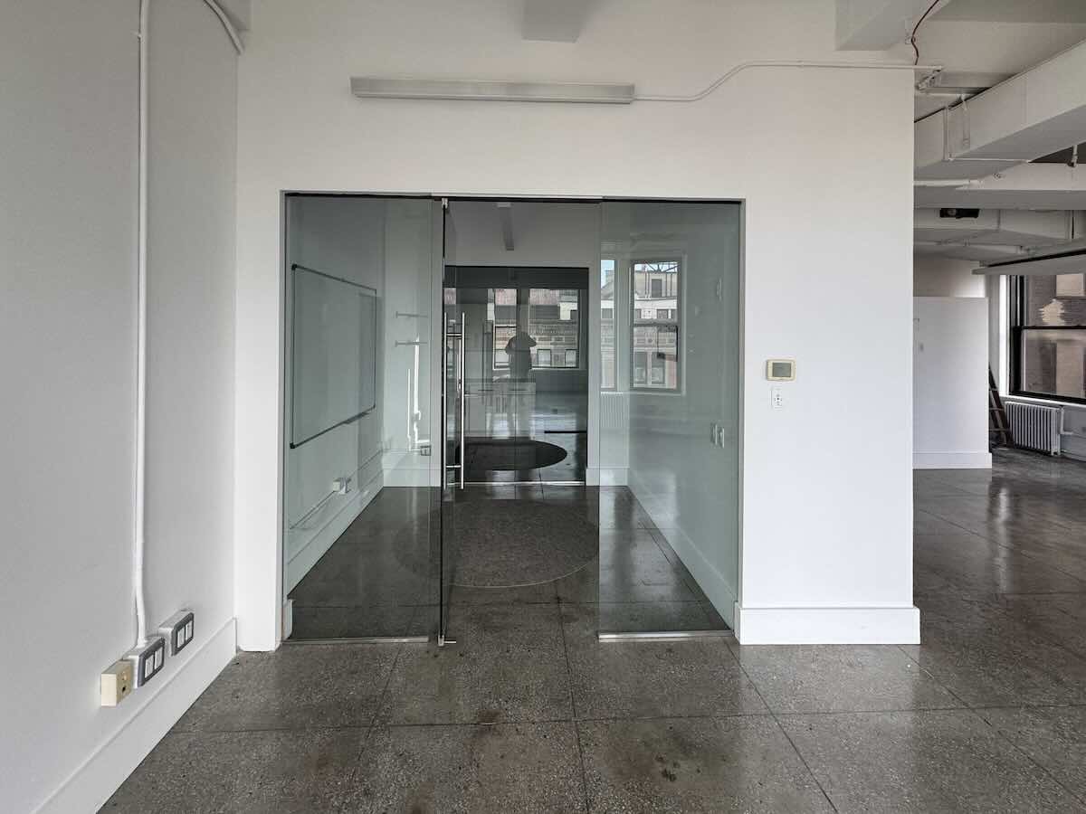 Modern office with glass walls and large window at 215 Park Ave. S