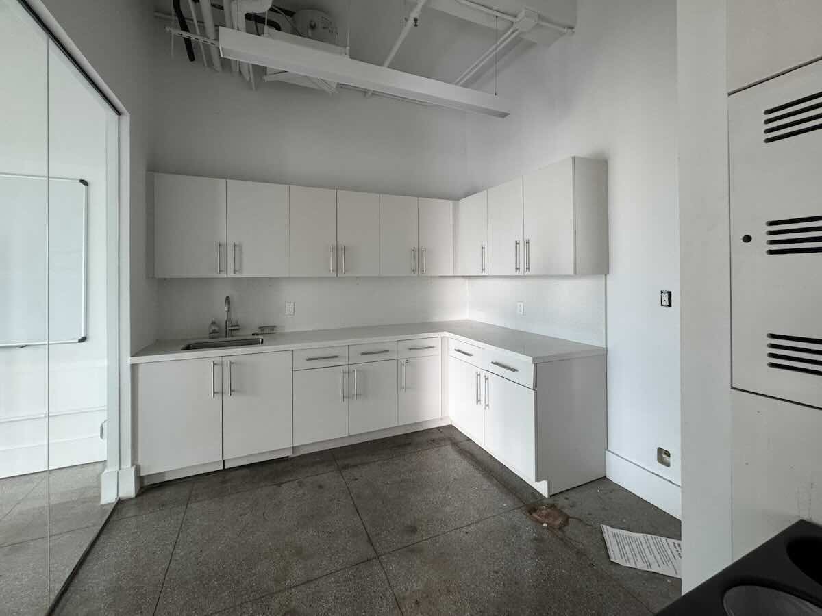 Modern kitchenette with white cabinets and glass door