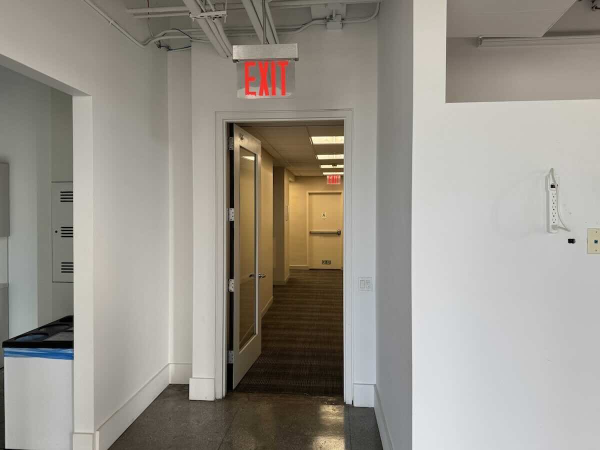 Office hallway on 215 Park Ave South, NYC with open door and exit sign.