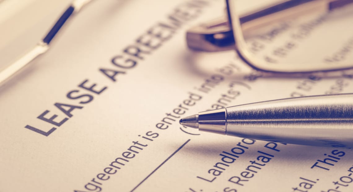 Close-up view of lease agreement document with pen and partial eyeglasses on top